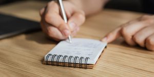 crop person taking notes in diary during studies